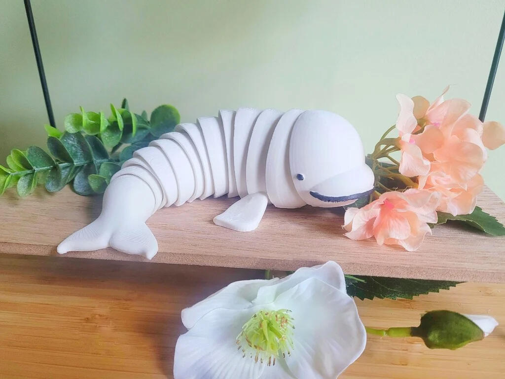 A 3D printed, articulated fidget toy modeled to look like a beluga. The beluga's body is made of multiple interlocking segments that allow him to bend and flop around.