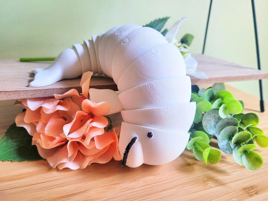 A 3D printed, articulated fidget toy modeled to look like a beluga. The beluga's body is made of multiple interlocking segments that allow him to bend and flop around.