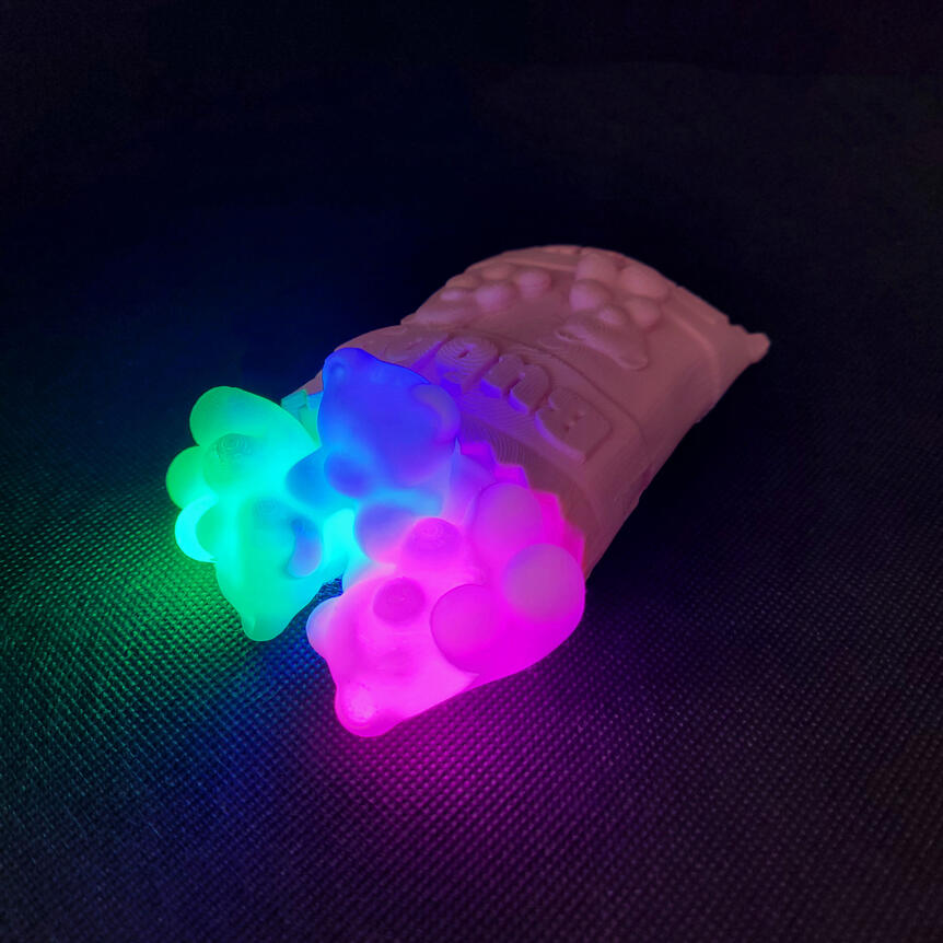 Small 3D printed light made to look like a spilled bag of gummy bears. Each gummy bear is illuminated from the inside with a different color light. There are three gummy bears: green, blue, magenta.