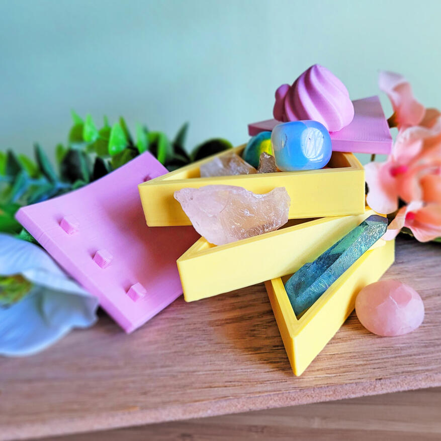 Untitled A pink and yellow 3D printed boxe, modeled to look like a slice of cake. The box has 3 compartments, each one a "layer" of cake. There is a small decoration on the top of it. The box is open, showing how all three compartments swivel around an axis. Severa